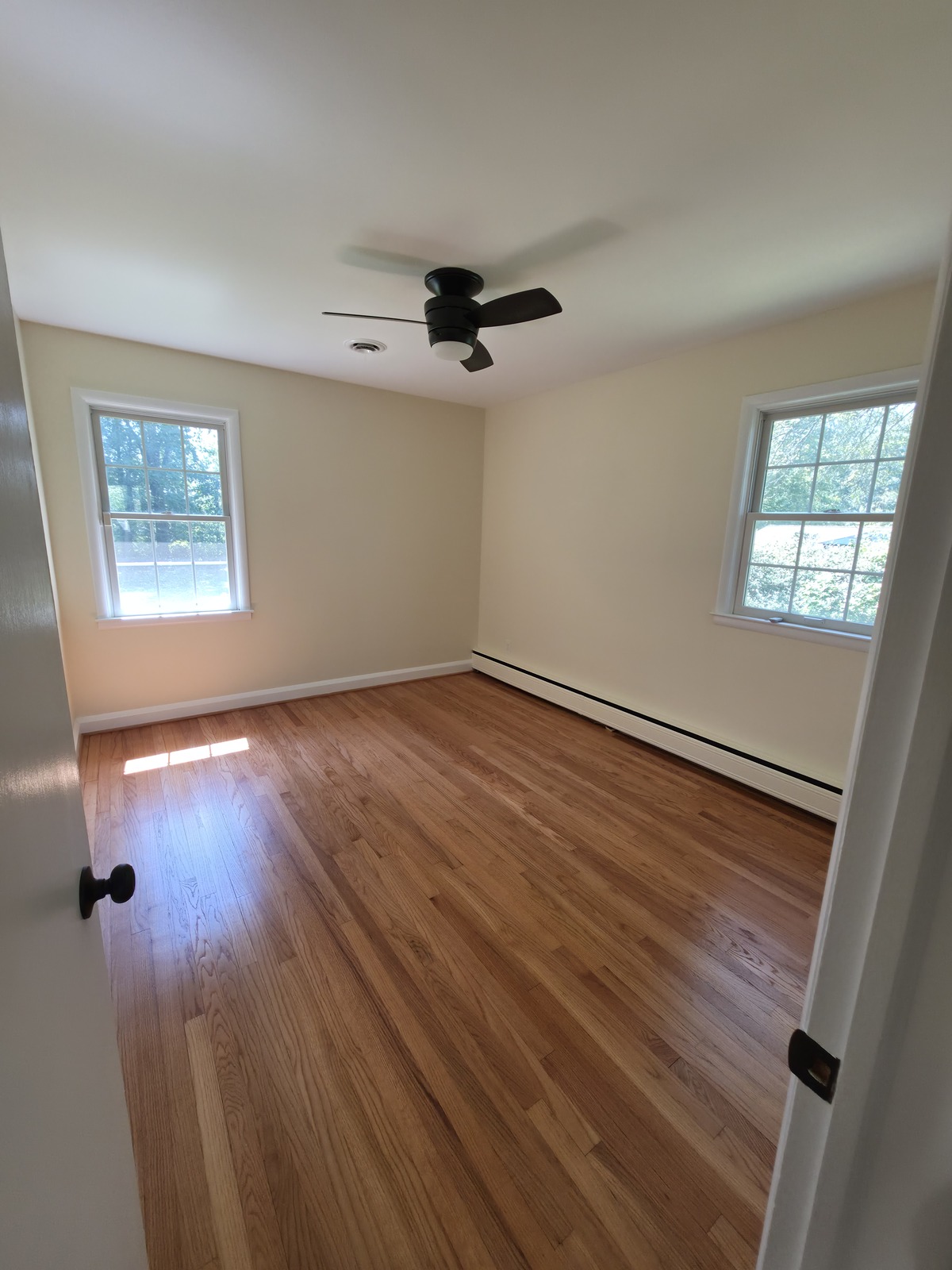 Painted bedroom with white trim and refinished hardwood