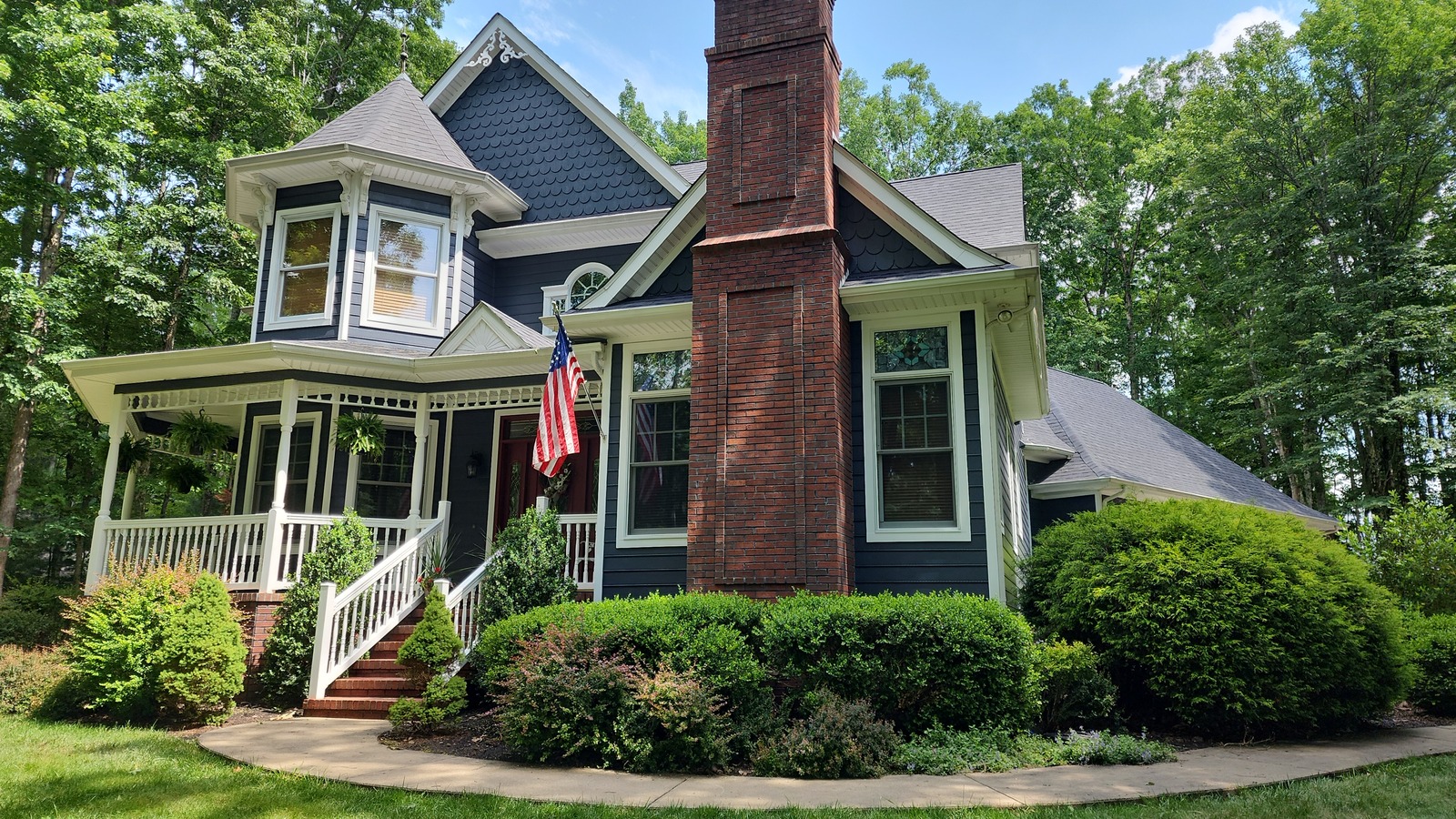 Blue house exterior with white trim, porch and brick chimney
