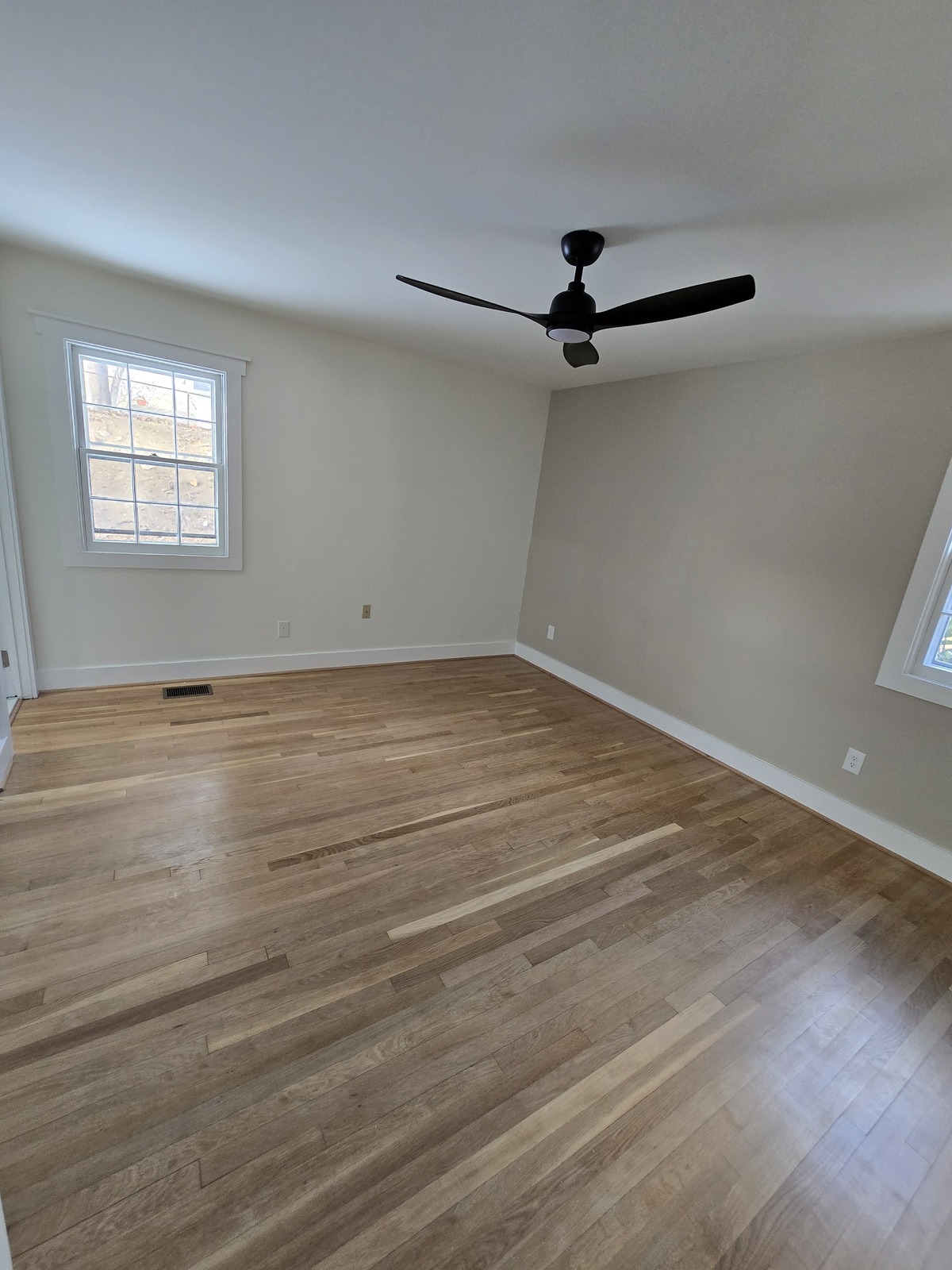 Natural wood floor in a neutral-painted room with white baseboards
