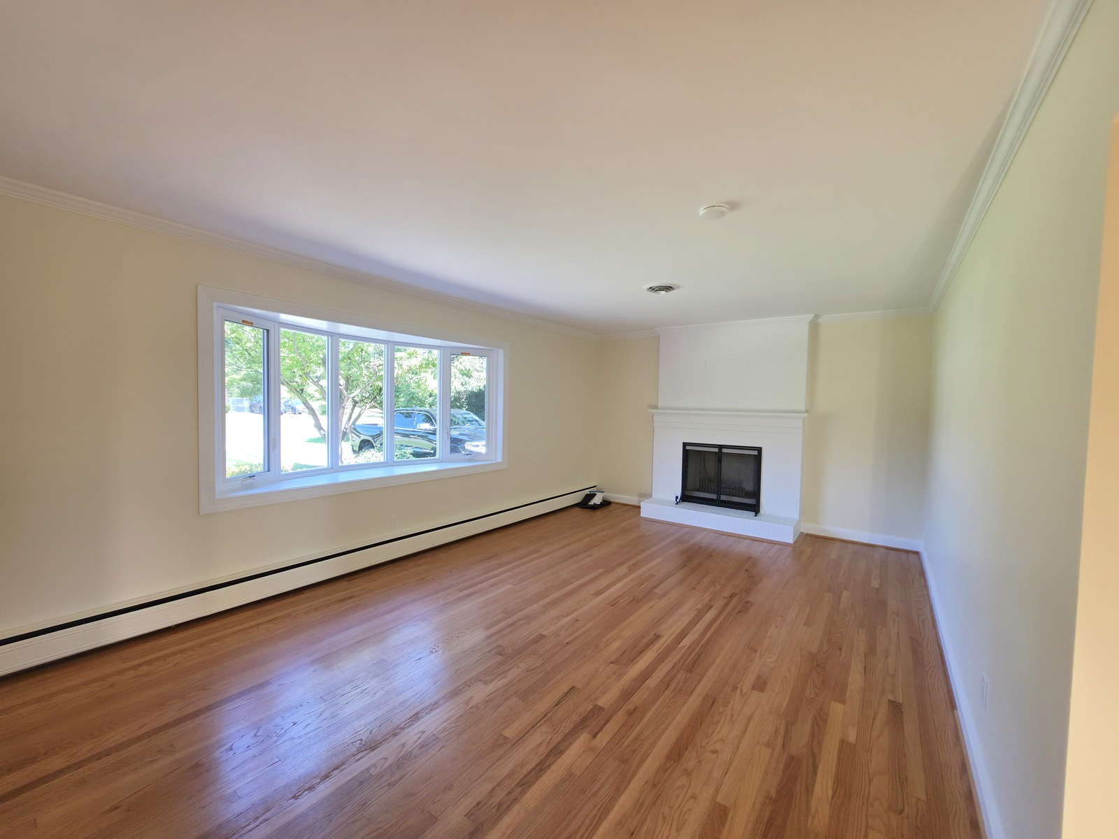 Cream-painted living room with fireplace, white trim and refinished hardwood