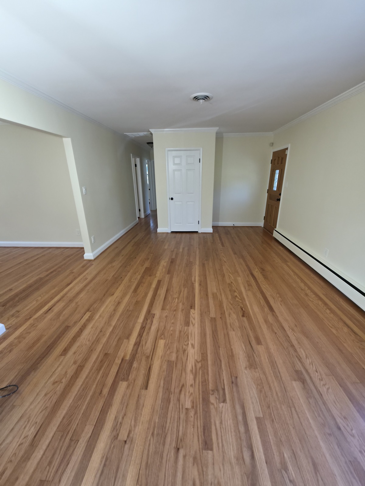 Cream-painted room with a white closet door and refinished hardwood flooring